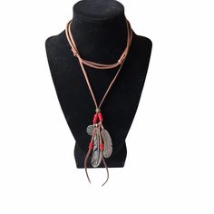 a necklace on a mannequin with red beads and feathers hanging from the neck