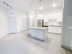 an empty kitchen and living room with white cabinets