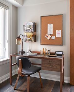 a desk with a chair and a bulletin board on the wall in front of it