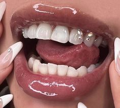 a woman's mouth with white and pink nail polish on her nails, holding up the