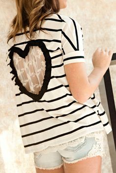 a woman wearing shorts and a striped shirt with a heart on the back, standing next to a railing