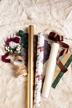 three different types of wrapping paper on top of a white blanket next to some ribbons