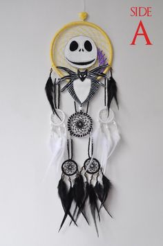 a white and yellow dream catcher with a skeleton face on it's side, hanging from the wall