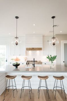 three stools are sitting at the bar in this modern kitchen with white cabinets and an island