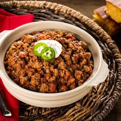 a bowl filled with chili and topped with a green jalapeno slice on top