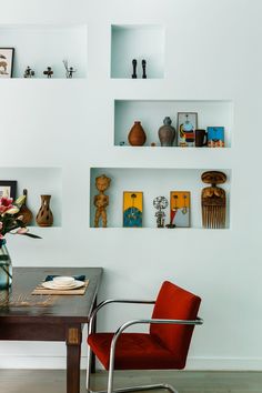 a room with some shelves on the wall and a chair in front of a table