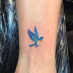 a small blue bird tattoo on the ankle