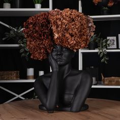 a black mannequin head sitting on top of a wooden table covered in flowers