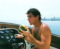 a shirtless man drinking from a coconut on a boat