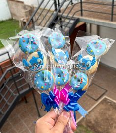 a hand holding a bunch of decorated donuts with blue icing and sprinkles