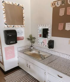 a bathroom sink sitting under a mirror next to a wall mounted paper dispenser