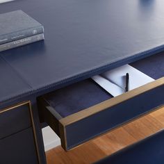 a blue desk with two drawers and a book on the top one has a pen in it