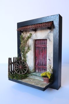 a miniature house with a red door and wheel