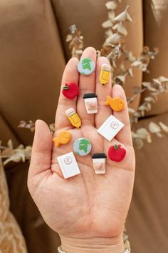 a person is holding several small magnets in their palm, with fruit and vegetables on them