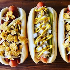 three hot dogs with toppings on them sitting next to each other