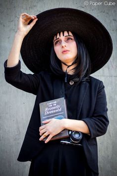 a woman wearing a black hat and holding a book