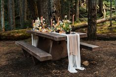 a table with candles and flowers on it in the woods