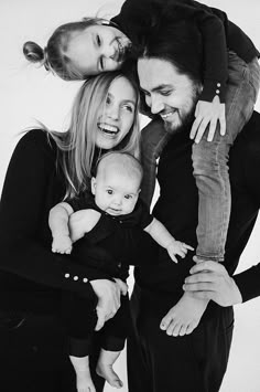 a man and woman holding a baby while posing for a photo with two other people