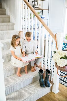 two children sitting on the stairs reading a book