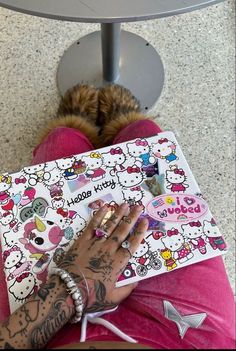 a person sitting on the ground with a hello kitty book