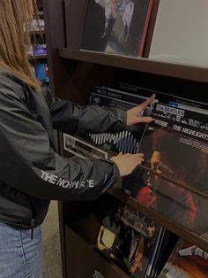 a woman is looking at the records on display in a music store while holding her hand out