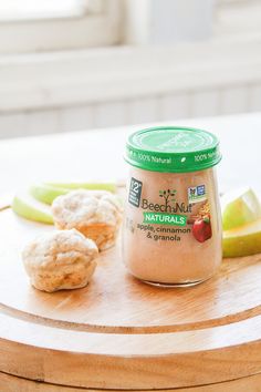 a jar of peanut butter sitting on top of a wooden table next to some fruit