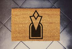 a door mat with an arrow in the center on a tile floor next to a black and white tiled wall