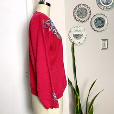 Herman Geist cerise pink pullover sweater with hand embroidered flowers. Openwork neck with single button on the back. Openwork decorative knit trim at the cuffs. Rib knit waist. Hand embroidered flowers are plum, light and dark lavender and light and dark green. Made in Hong Kong. Material / 55% acrylic, 45% cotton Care / dry clean For accurate fit, please compare measurements to a similar garment that fits you well. Make allowance for clothes underneath and to allow garment to drape properly. Pink Embroidered Long Sleeve Sweater, Pink Long Sleeve Embroidered Sweater, Pink Pullover Sweater, Dark Lavender, Hand Embroidered Flowers, Cerise Pink, Pink Pullover, 1980s Vintage, Embroidered Flowers