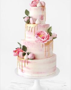 a three tiered cake with pink flowers and dripping icing on the top layer