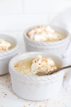 three small white bowls filled with pudding and topped with whipped cream, sprinkled with orange zest