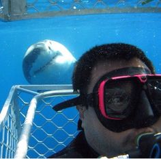 a man wearing goggles is taking a selfie with a shark in the background