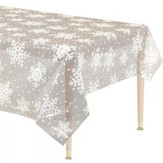 a table covered in snowflakes on top of a white table cloth with wooden legs