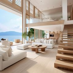 a living room filled with white furniture next to a large open floor plan overlooking the ocean