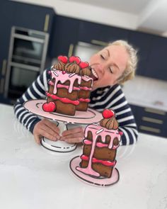 a woman holding two cakes with pink frosting