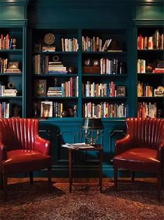 two red chairs sitting in front of a bookshelf