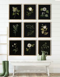 a white table topped with vases filled with flowers next to black framed art pieces