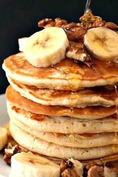 a stack of pancakes topped with bananas and walnuts