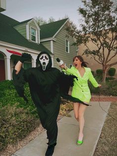 a woman in a green dress is walking down the sidewalk with a ghost costume on