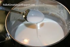 milk being poured into a saucepan with a spoon