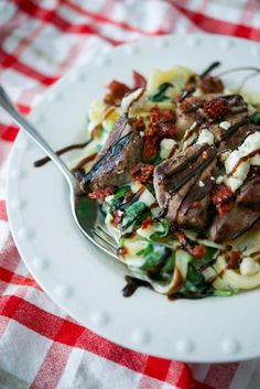 steak and gorgonzolla alfredo on a white plate with a red checkered tablecloth