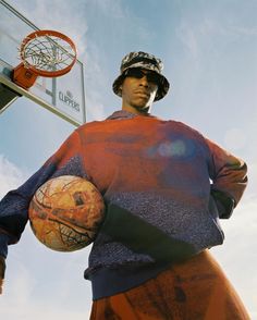 a man holding a basketball in his right hand and standing next to a basketball hoop