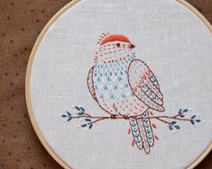 an embroidered bird sitting on top of a wooden hoop