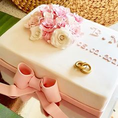 a wedding cake decorated with flowers and two gold rings for the couple's anniversary