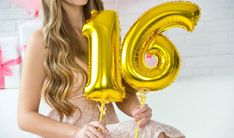 a young woman is holding some balloons in front of her face