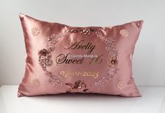 a pink satin pillow with the words happily sweet on it and flowers in gold lettering