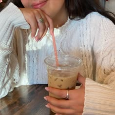 a woman sitting at a table with a drink in her hand