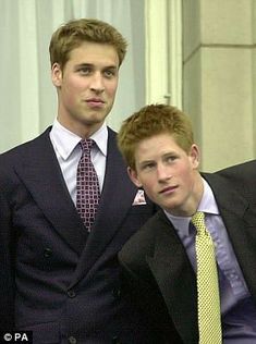 two men in suits and ties standing next to each other with one man looking at the camera