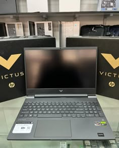 an open laptop computer sitting on top of a glass table in front of some black boxes