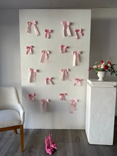 several pieces of pink paper tied to a wall with bows on it and two white chairs in the background