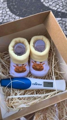 a pair of baby shoes in a box with a thermometer